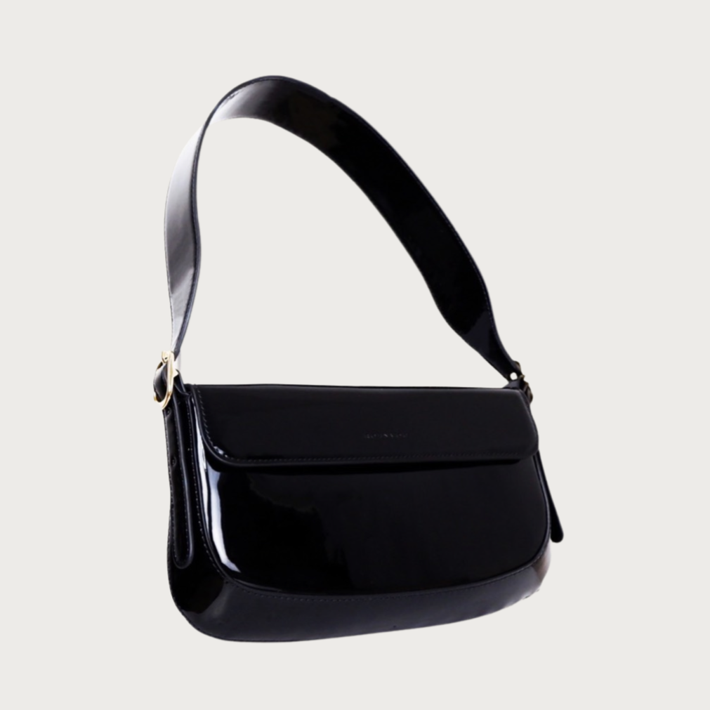 Unique baguette bag made by glossy vegan leather with asymmetrical shape. Features magnet closure and an adjustable and removable handle.