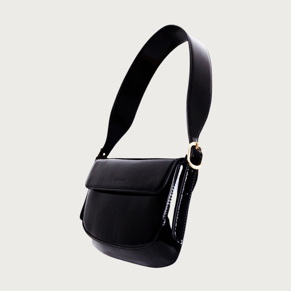 Unique baguette bag made by glossy vegan leather with asymmetrical shape. Features magnet closure and an adjustable and removable handle.